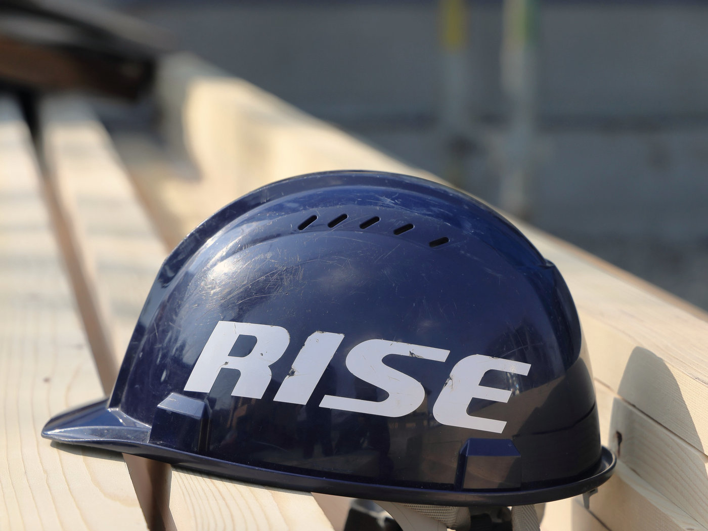 木材の上に置かれた、RISEのロゴ入りの紺色のヘルメット